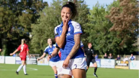 Ross Halls Natasha Thomas celebrating scoring a hat-trick, against Cheltenham by holding up three fingers at the AGL Arena in Felixstowe.