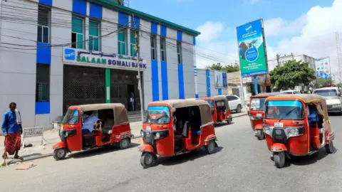 Reuters Rickshaw taxis drive past the Salaam Somali Bank in Wadajir district of Mogadishu, Somalia October 14, 2020.