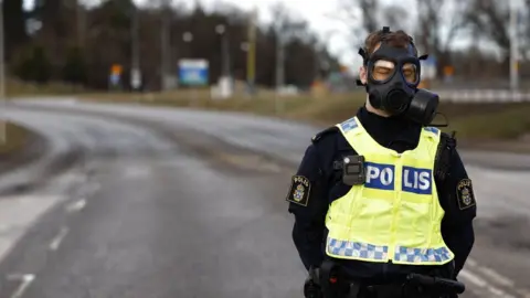 AFP Police officer wearing gas mask standing at the scene after emergency services were called to Sweden's Security Service headquarters