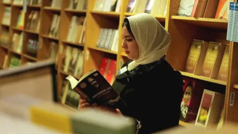 Reuters File photo showing a woman reading a book on a floating book fair docked at Port Said in Egypt (5 January 2023)