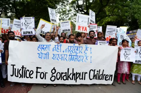 Getty Images Protestors hold placards and shout slogans against the deaths of at least 64 children at the Baba Raghav Das Hospital in Gorakhpur.