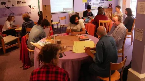 A picture of people sitting around tables at a community centre