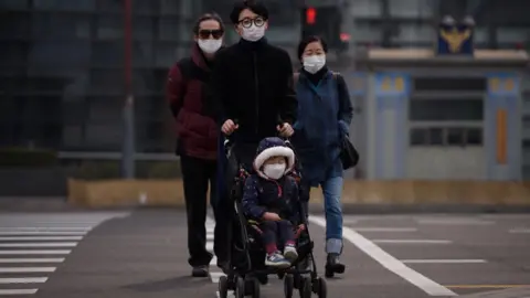 AFP Korean family with little child, all wearing face masks