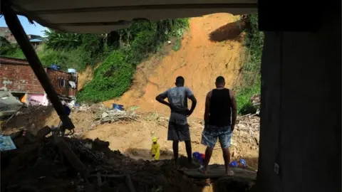 Reuters Men stand on the debris of a house which collapsed during a landslide caused by heavy rains at at Jardim Monte Verde, in Ibura neighbourhood, in Recife, Brazil, May 30, 2022