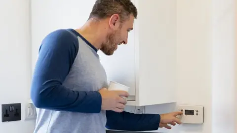 Getty Images Man turning down thermostat
