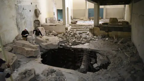 Iraqi State Board of Antiquities and Heritage Crater in floor caused by IS bomb