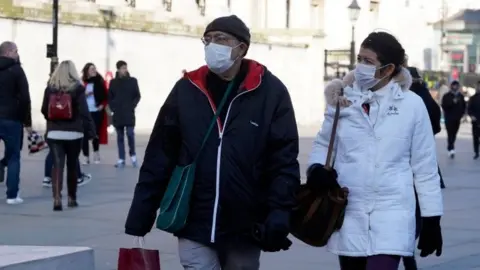 Getty Images Pedestrians wear surgical masks as they shop in central London