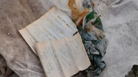 The letters alongside a smashed bottle