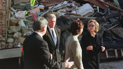 Getty Images/ JOYCE NALTCHAYAN US President Bill Clinton (2D L), his wife, Hillary (R) and British Prime Minister Tony Blair's wife, Cherie (2D R), view 03 September the damage caused by a terrorist bomb that killed 28 people on 15 August. The Clintons later took a walk in the High Street.