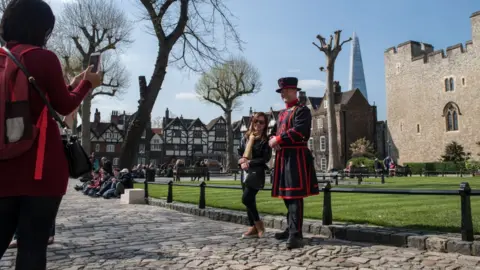 Getty Images Tourists have photos taken with a Beefeater at the Tower of London