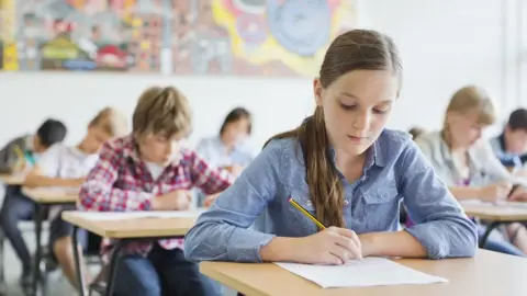 Getty Images A group of students, dressed in their own clothes, doing a test in a classroom setting