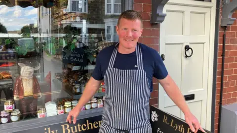 Butcher standing outside shop