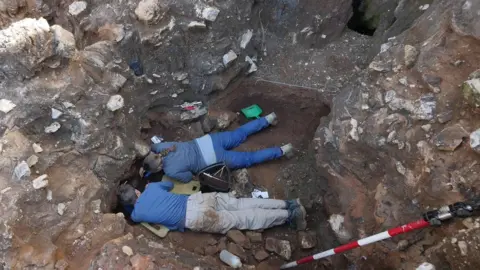 LA TROBE UNIVERSITY Two people dig in Drimolen quarry near Johannesburg