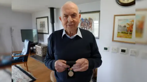 Dawid Wojtowicz/BBC Brian Cantle holding his Nuclear Test Medal