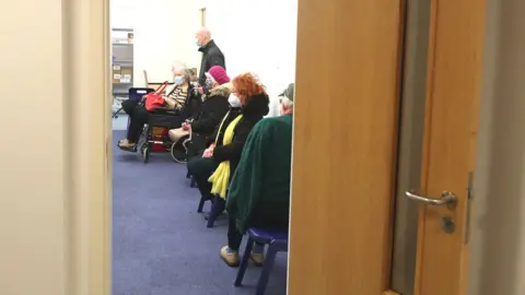 Getty Images patients sitting spaced out in a GP surgery