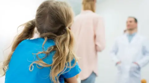Getty Images Child with mum and doctor