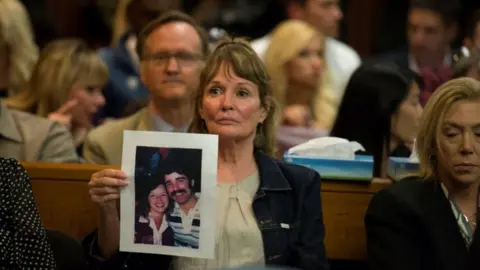 Reuters Melanie Barbeaux holds a photo of victims of the Golden State Killer in the courtroom