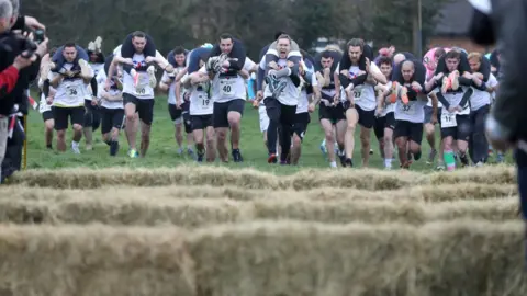 PA Competitors make their way off the start line as they take part in the annual UK Wife Carrying Race