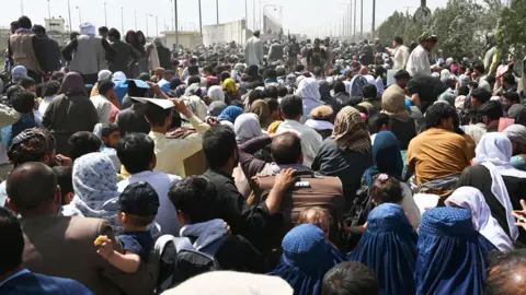 Getty Images Afghans gather on a roadside near the military part of the airport in Kabul, August 20, 2021