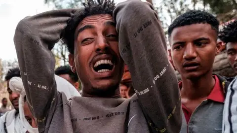 AFP A man reacts as people gather around the body of a young man that witnesses say was shot by security forces after breaking curfew, capital of Tigray on February 27, 2021.