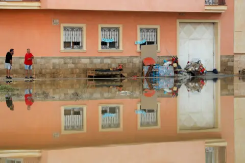 Susana Vera/Reuters Residents stand next to damaged belongings after torrential rains in Almoradi, near Alicante, Spain. 17 September 2019