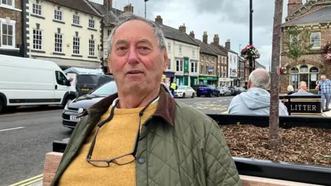 BBC Image of Roger Saunders sat on bench in Northallerton