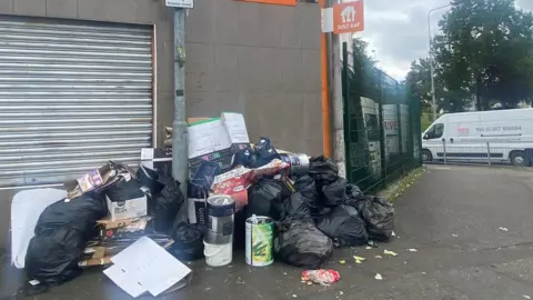 rubbish accumulates outside a business in Drumchapel