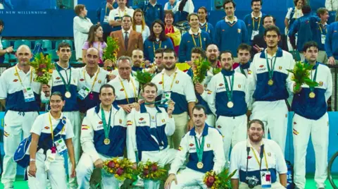 EPA The basketball team wearing the gold medals they had to return - Fernando Martín Vicente can be seen in a brown jacket, standing behind the players