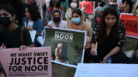 AAMIR QURESHI/AFP via Getty Images Women rights activists hold placards and candles during a protest rally against the brutal killing of Noor Mukadam, the daughter of a former Pakistani diplomat who was found murdered at a house in Pakistan's capital on July 20, in Islamabad on September 22, 2021.