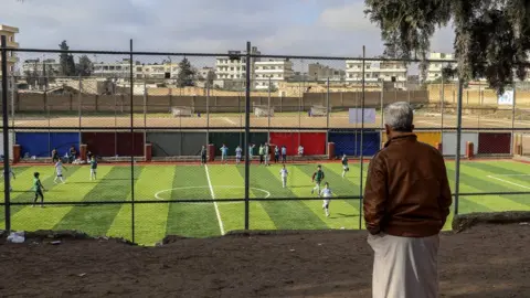 EPA A man watches a football match in Manbij, northern Syria (31 December 2018)