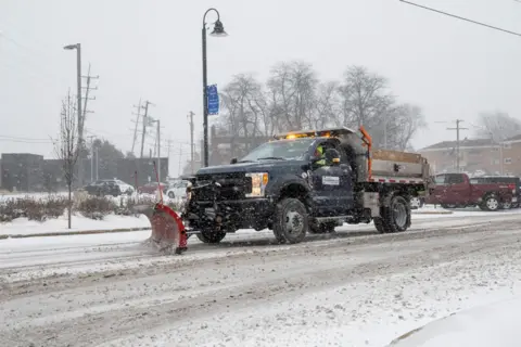 Stephen Chung / Alamy Stock Photo : A snow plough passes as heavy snowfall begins in a western suburb of Chicago as a winter storm arrives in the Midwest.