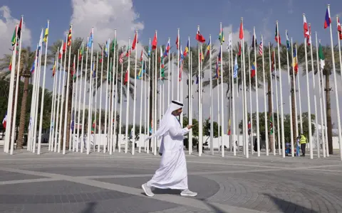 Getty Images A man walks past flags outside the site of COP28 in Dubai on 29 November