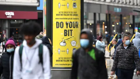 AFP Shoppers wear facemasks as they walk along the streets of Manchester,