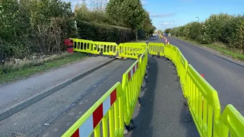 Liz Skelt High visibility road barriers and traffic cones cutting the road down to one lane.