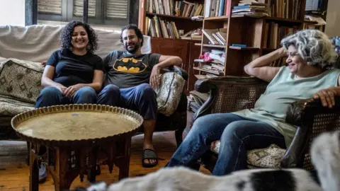 AFP Egyptian activist and blogger Alaa Abdel Fattah (C) smiles next to his mother Laila Soueif (R) and sister Mona Seif (L) in Giza (17 May 2019)