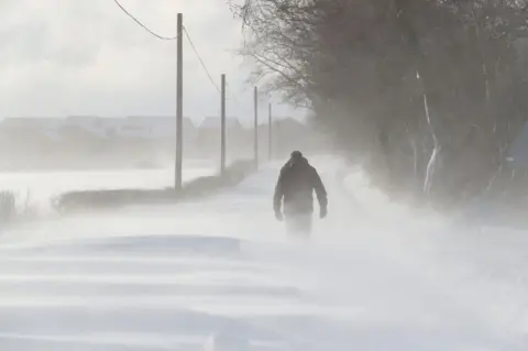 PA A man walking in snowy conditions in Larbert, Scotland