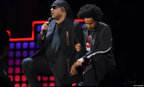 Getty Images Stevie Wonder and his son kneeling