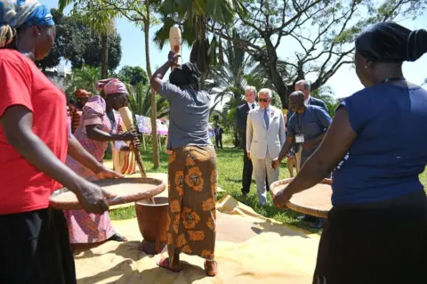 PA Prince Charles watches women pounding.