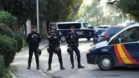 Getty Images Three Spanish policeman block a road following a letter bomb explosion at the Ukraine's embassy in Madrid on Wednesday