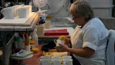 PA Media A worker prepares chinaware at a pottery factory in Stoke-on-Trent where the official Coronation chinaware is produced on behalf of Royal Collection Trust