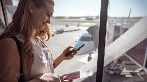 Getty Images Woman using phone in an airport