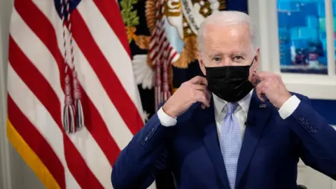 Getty Images Biden puts on a facemask