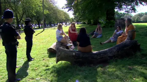 A group of students in a Bristol park with police enforcing coronavirus restrictions