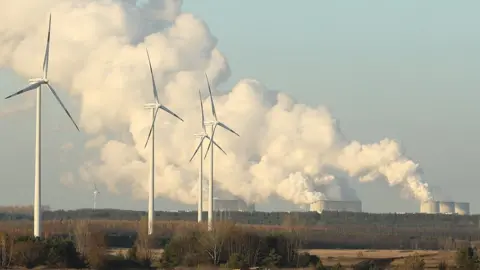 Getty Images Wind turbines and a power station