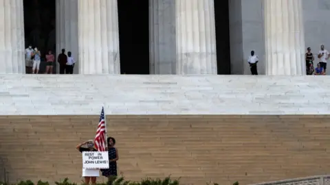 Reuters People watch as a hearse with the flag-draped casket of late Rep. John Lewis, (D-GA), drives by the Lincoln Memorial, in Washington, U.S., July 27, 2020