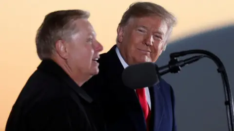 Reuters President Donald Trump listens to Senator Lindsey Graham during a campaign rally in Tupelo, Mississippi, November 26, 2018