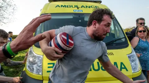 Getty Images A man carrying a keg runs past an ambulance