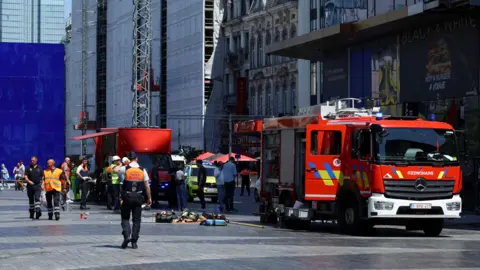 Red firetrucks are parked beside a building
