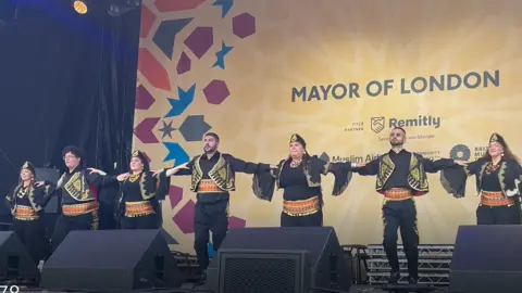 dancers in traditional costumes link arms on the stage