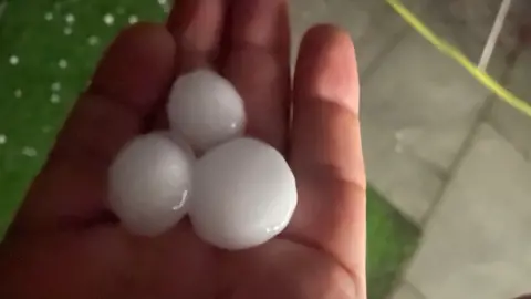 Steve Charlton Three large, white hailstones sit in the palm of a hand